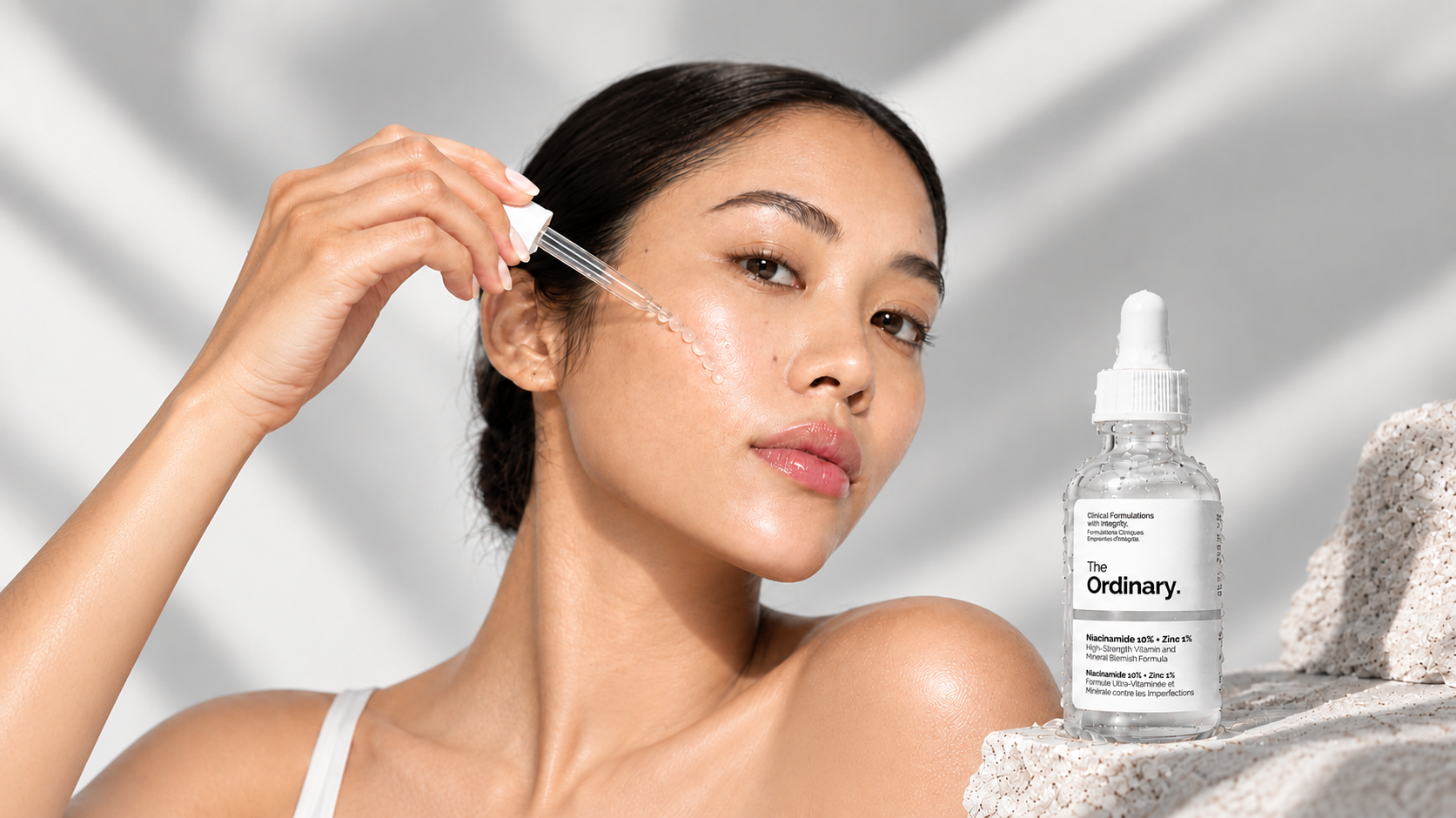 Woman applying Niacinamide 10% + Zinc 1% serum to her face