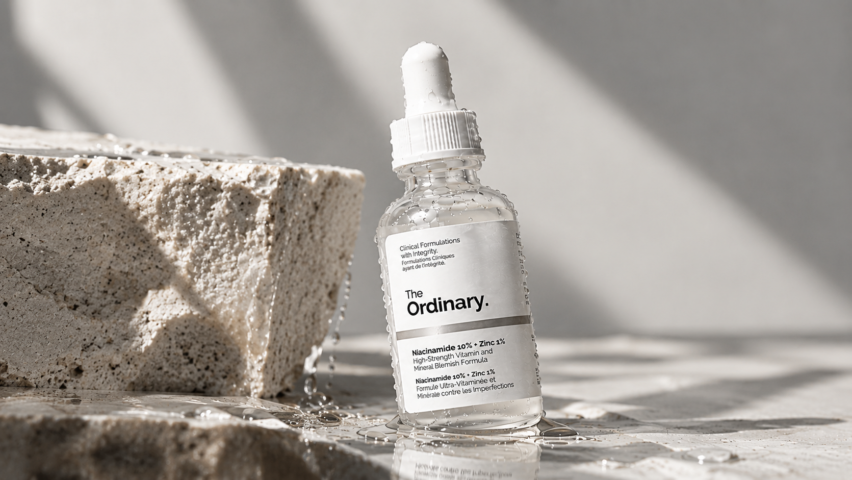 The Ordinary Niacinamide 10% + Zinc 1% serum displayed on a wet stone surface